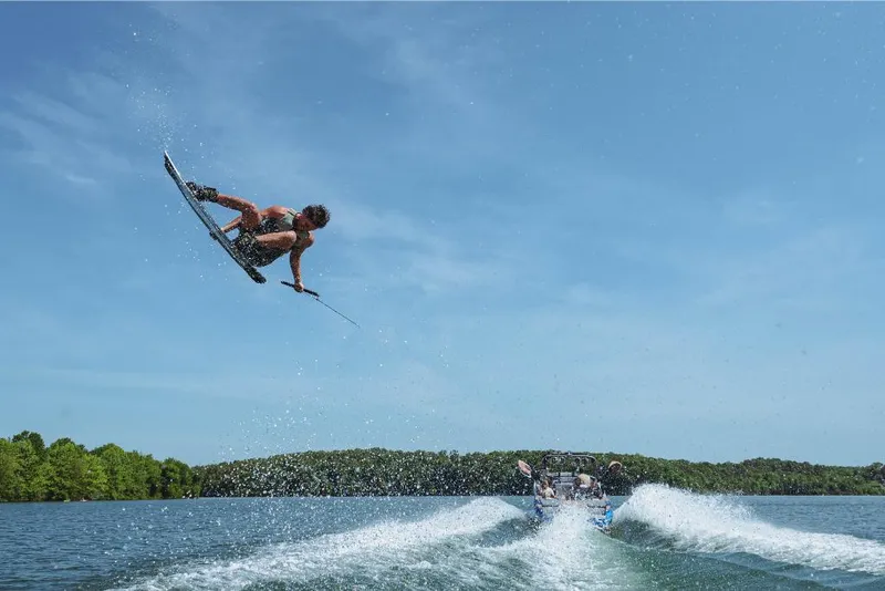 Slide: The Image of Wakeboarder performing aerial trick behind 2023 MasterCraft X22 boat on a lake. - 15