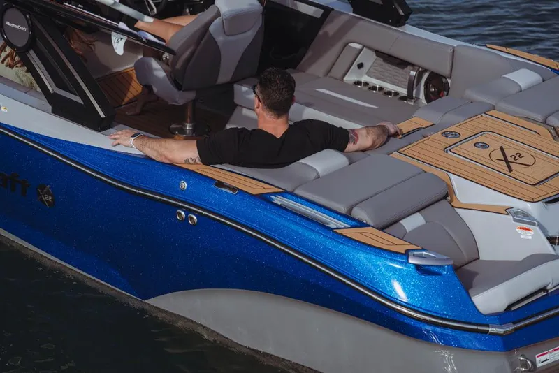 Slide: The Image of 2023 MasterCraft X22 boat with a man relaxing on the deck. - 6
