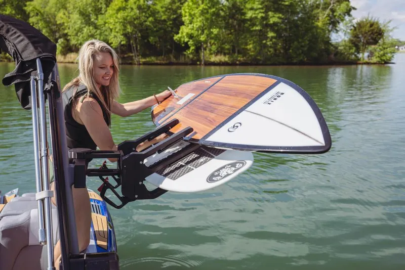 Slide: The Image of Woman on 2023 MasterCraft X22 boat holding a surfboard on a lake. - 7