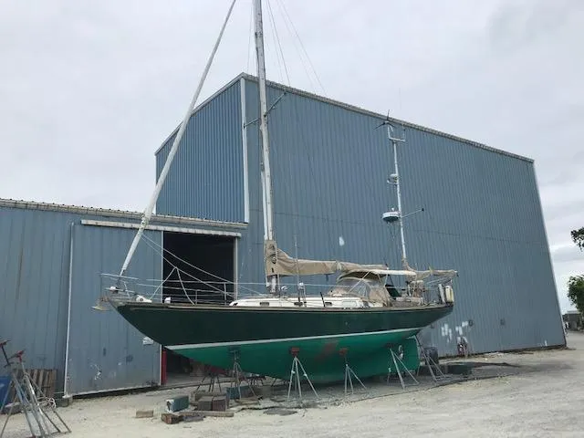 Slide: The Image of 1968 Hinckley Bermuda 40 sailboat on stands outside a blue warehouse. - 14