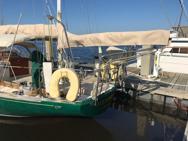 Slide: The Image of 1968 Hinckley Bermuda 40 sailboat docked at a marina, with beige canopy and life ring. - 3