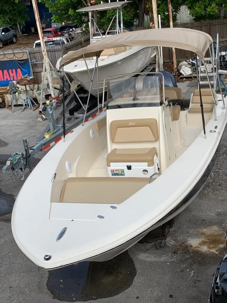 Slide: The Image of 2025 Scout 195 Sportfish boat with beige seating and canopy in a marina. - 3