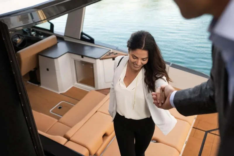 Slide: The Image of 2023 Aviara AV32 Outboard luxury boat interior with a woman being helped aboard. - 15