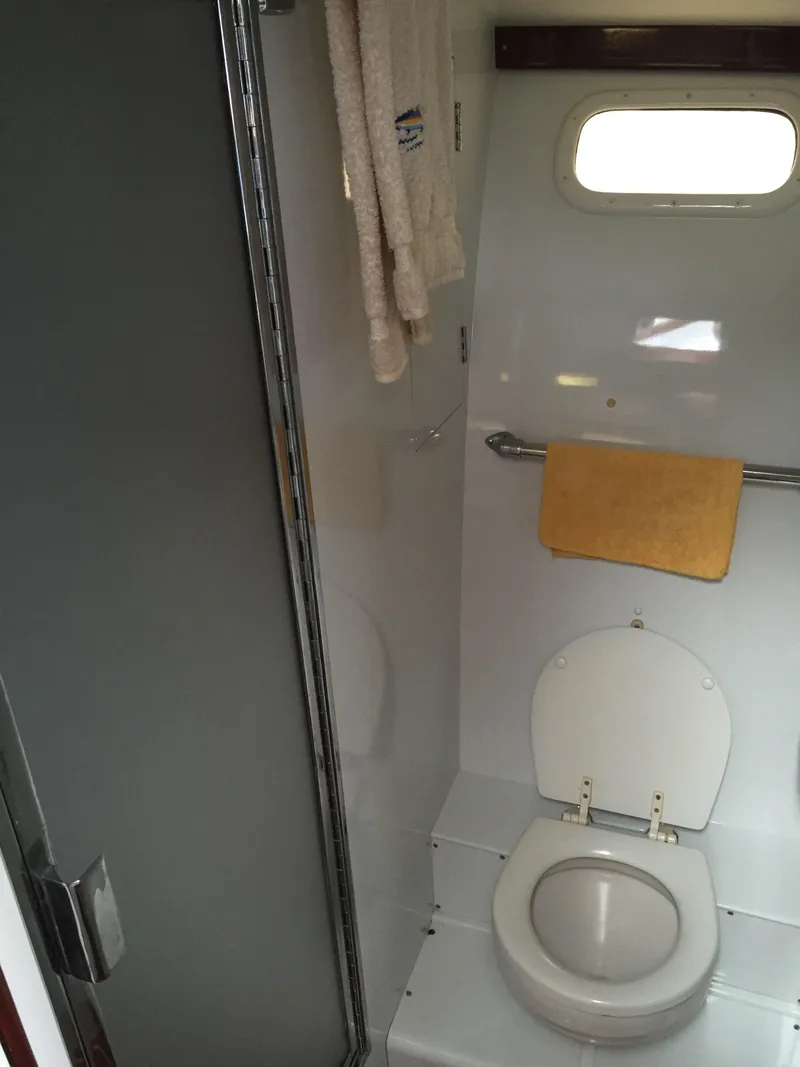 Slide: The Image of 1965 Rybovich 37 Sportfish bathroom with toilet, shower, and window. - 2