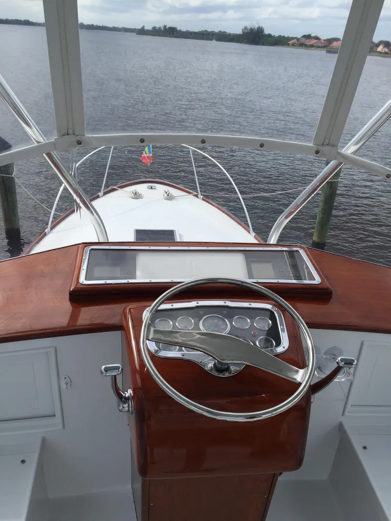 Slide: The Image of 1965 Rybovich 37 Sportfish boat helm with wooden dashboard on calm water. - 9