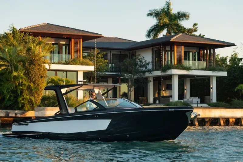 Slide: The Image of 2023 Aviara AV32 boat cruising near a luxurious waterfront home. - 12