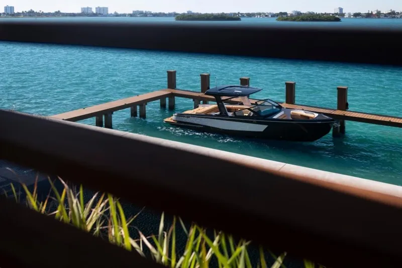 Slide: The Image of 2023 Aviara AV32 boat docked in clear blue water, viewed through wooden railings. - 4