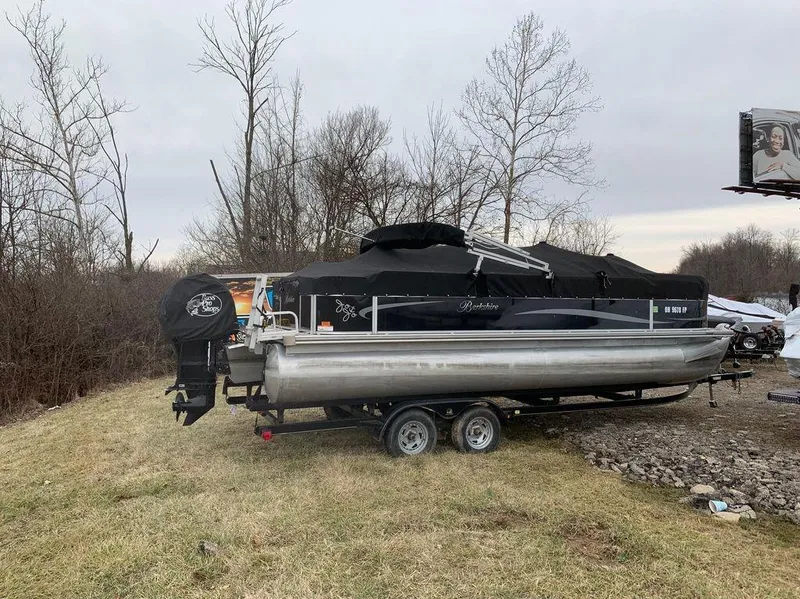 Slide: The Image of 2011 Berkshire 221 RFC LTD pontoon boat on trailer, parked on grass near trees. - 3