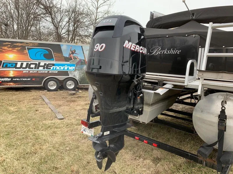 Slide: The Image of Outboard motor on a 2011 Berkshire 221 RFC LTD boat, parked on grass. - 4