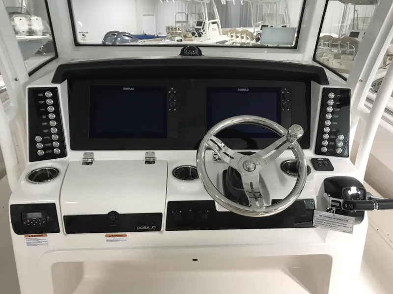 Slide: The Image of 2024 Robalo R302 boat dashboard with dual Simrad displays and stainless steel steering wheel. - 9