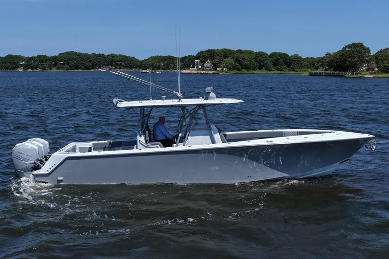 Slide: The Image of 2021 SeaVee 370z boat cruising on a calm lake with scenic shoreline. - 14