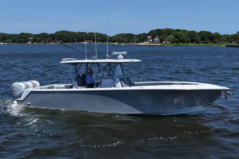 Slide: The Image of 2021 SeaVee 370z boat cruising on a calm lake with lush green shoreline. - 15