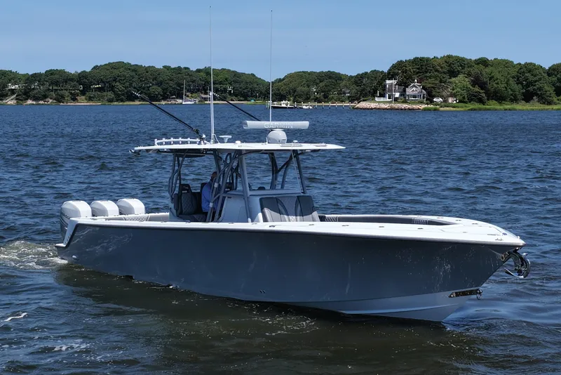 Slide: The Image of 2021 SeaVee 370z boat cruising on a calm lake with scenic shoreline. - 16