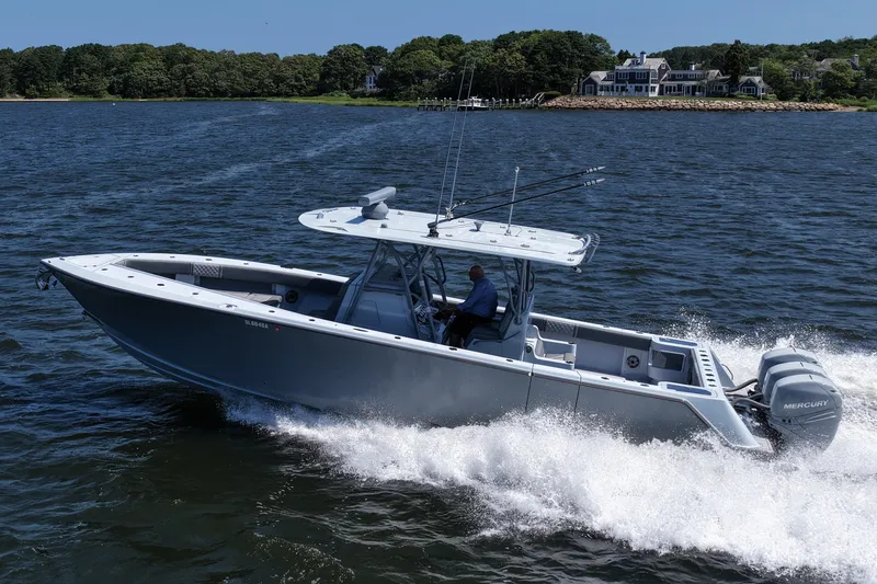 Slide: The Image of 2021 SeaVee 370z boat cruising on water with scenic shoreline background. - 2