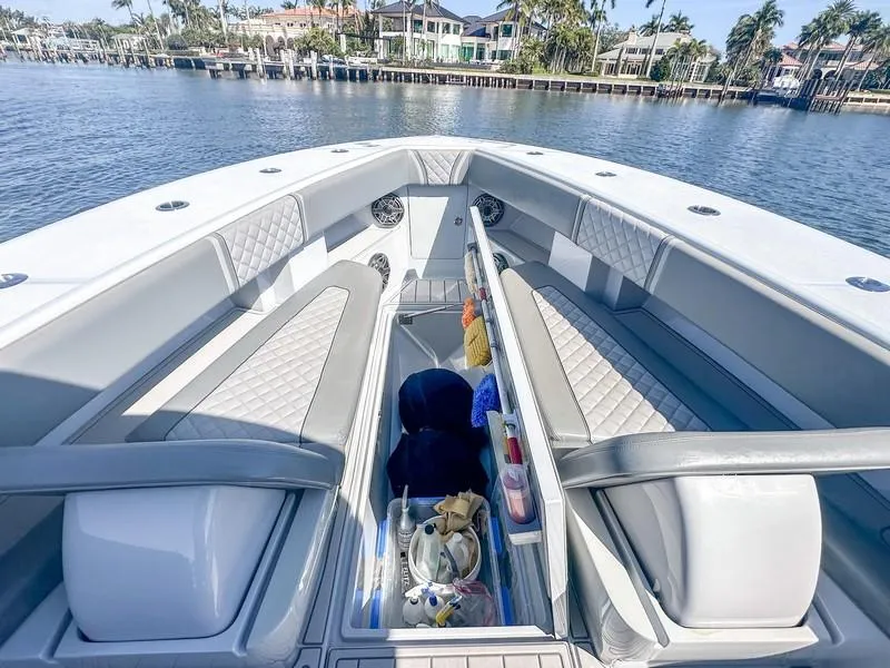 Slide: The Image of 2021 SeaVee 370z boat interior with cushioned seating and storage, docked by waterfront homes. - 26