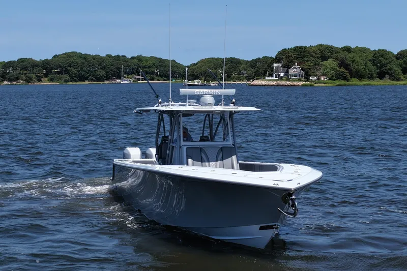 Slide: The Image of 2021 SeaVee 370z boat cruising on a calm lake with lush green shoreline. - 3