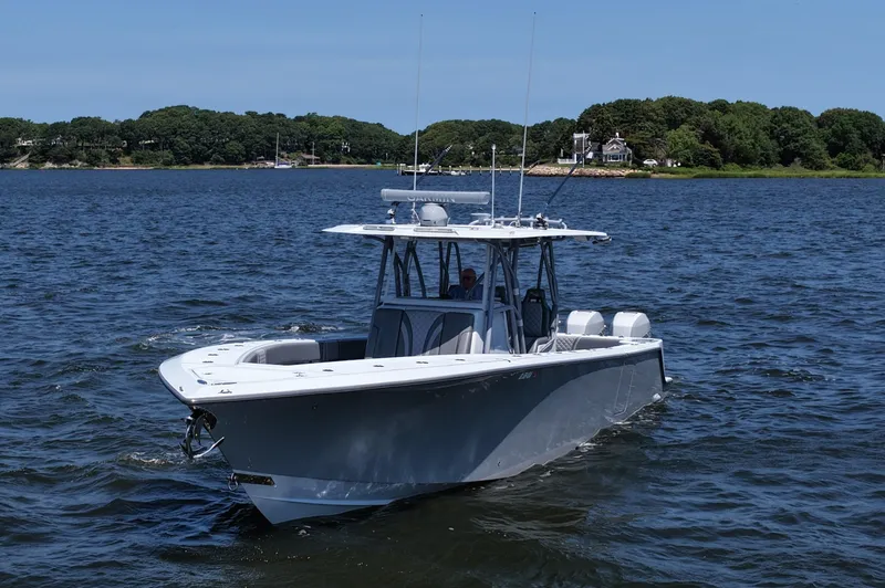 Slide: The Image of 2021 SeaVee 370z boat cruising on a calm lake with lush green shoreline. - 5