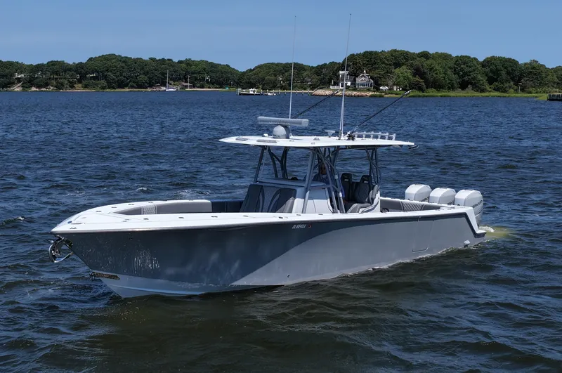 Slide: The Image of 2021 SeaVee 370z boat cruising on a calm lake with lush green shoreline. - 6
