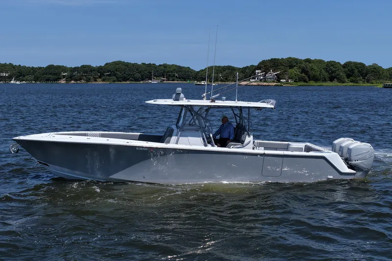 Slide: The Image of 2021 SeaVee 370z boat cruising on a calm lake with lush green shoreline. - 8