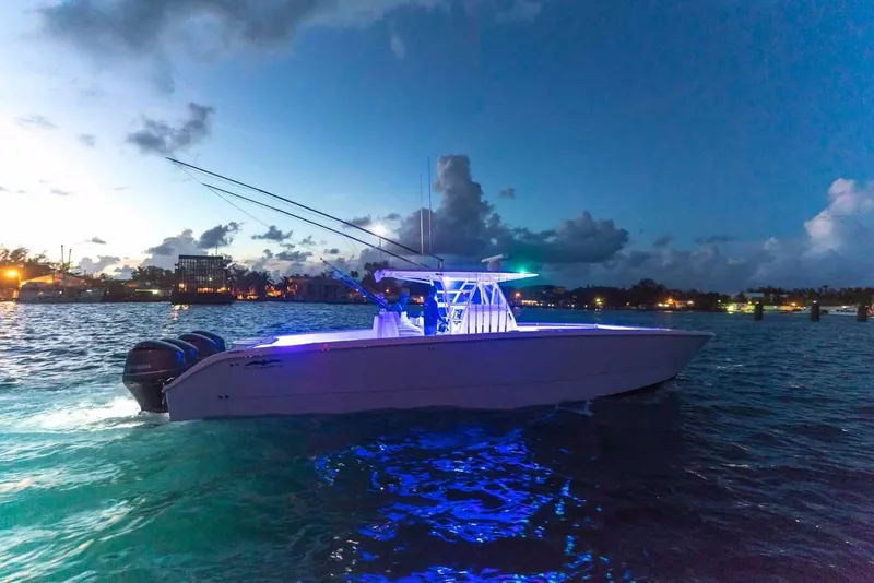 Slide: The Image of 2024 Invincible 40 Catamaran with blue LED lights cruising at dusk. - 6