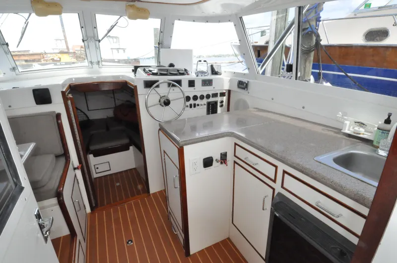 Slide: The Image of 1974 Bertram 31 Sportfisher interior with helm, kitchenette, and seating area. - 14