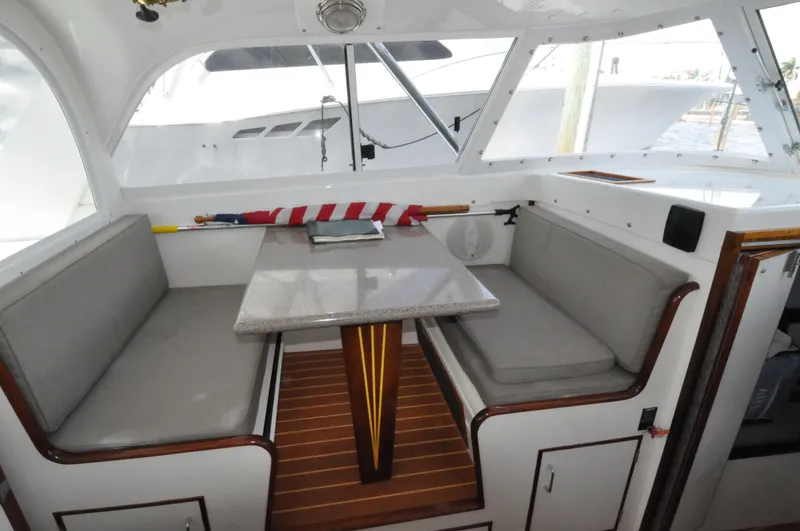 Slide: The Image of 1974 Bertram 31 Sportfisher interior with cushioned seating and table. - 4