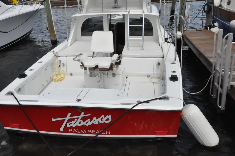 Slide: The Image of 1974 Bertram 31 Sportfisher docked, rear view with Tabasco Palm Beach text. - 5