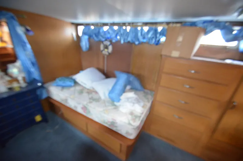 Slide: The Image of 1964 Chris-Craft Constellation cabin interior with bed, wooden drawers, and blue curtains. - 17