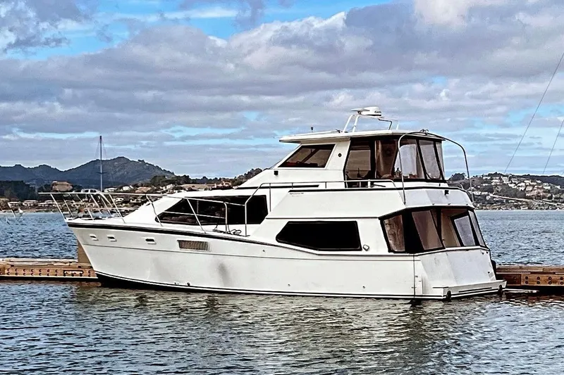 Slide: The Image of 1988 Kadey-Krogen Silhouette yacht docked on a serene lake with mountainous backdrop. - 2