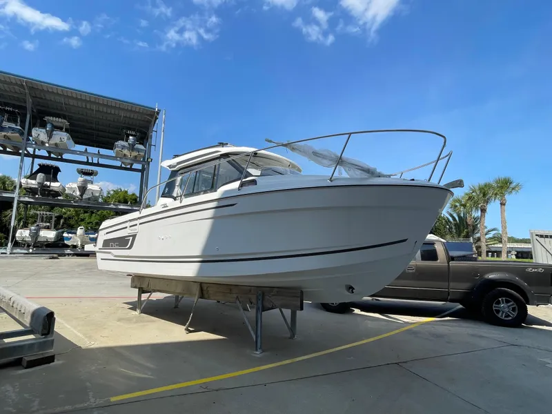 The Image of 2024 Jeanneau NC 795 boat on display at a marina under a clear blue sky. - 0