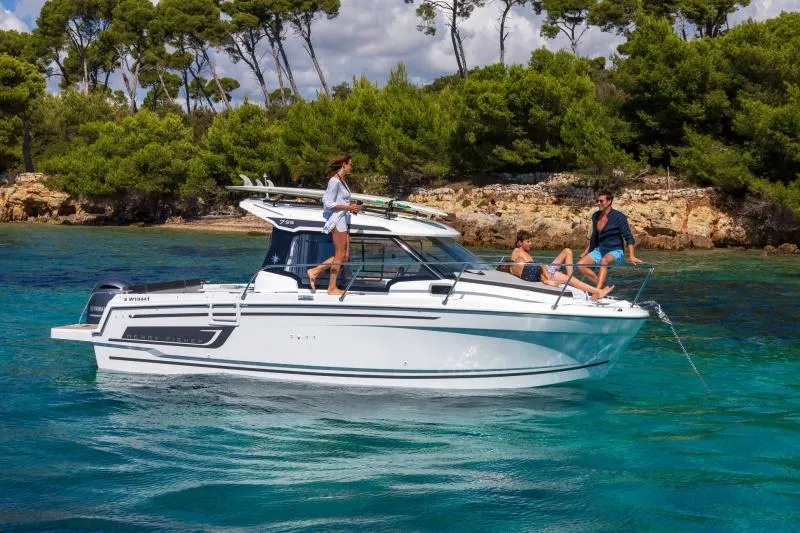Slide: The Image of 2024 Jeanneau NC 795 boat cruising in clear blue waters with people onboard. - 18