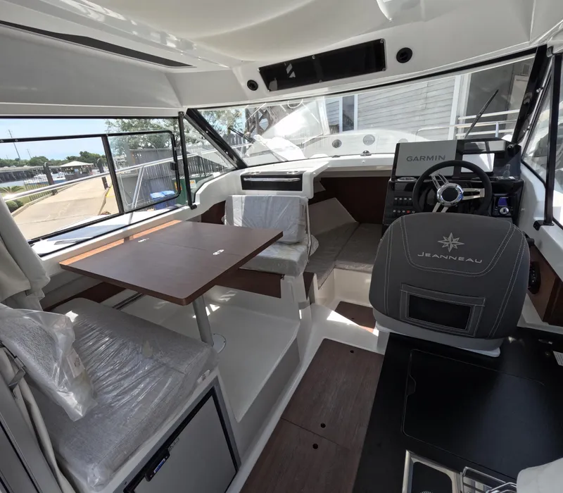 Slide: The Image of 2024 Jeanneau NC 795 boat interior with helm, seating, and dining area. - 2