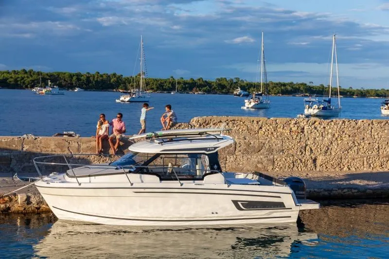 Slide: The Image of 2024 Jeanneau NC 795 boat docked by a stone wall with people nearby. - 20