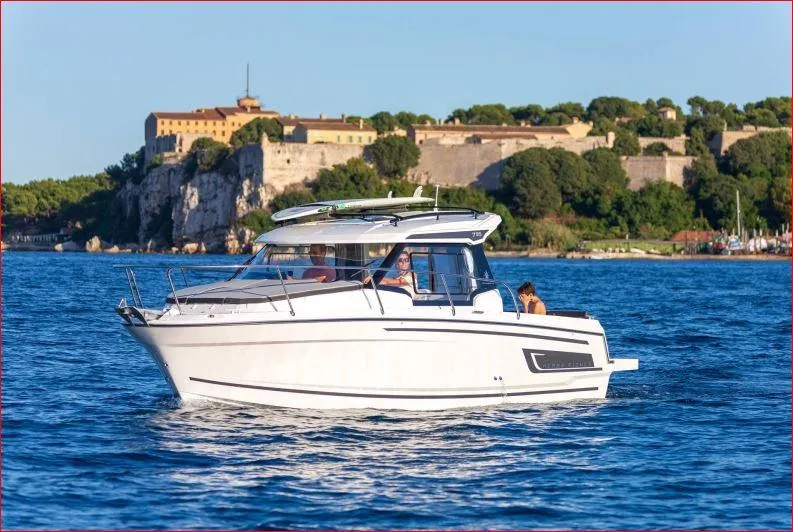 Slide: The Image of 2024 Jeanneau NC 795 boat cruising near a historic coastal fort. - 8