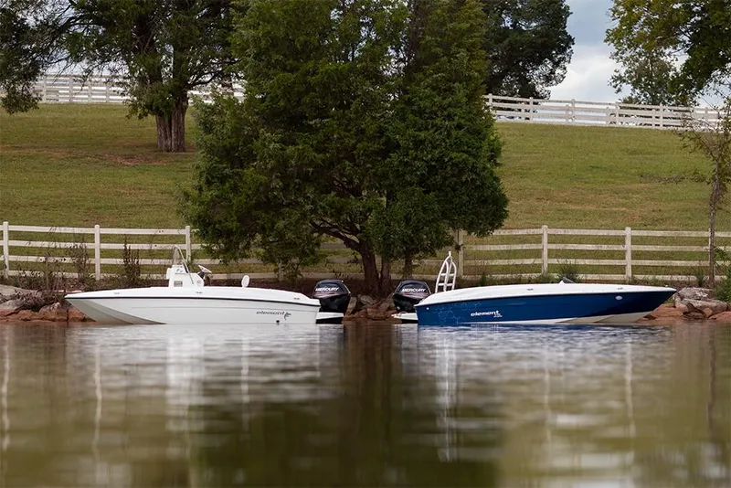 Slide: The Image of 2023 Bayliner Element E18 boats docked by a lakeside with trees and a white fence. - 13