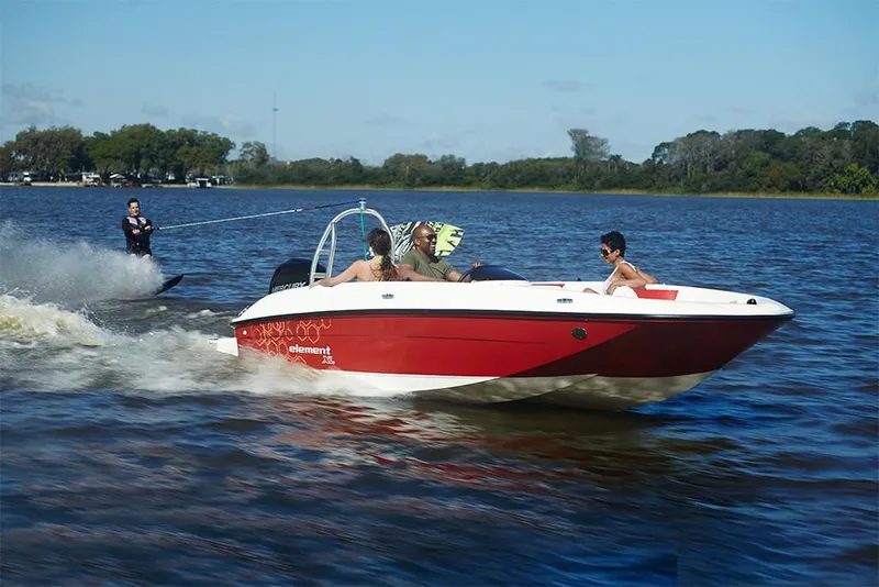 Slide: The Image of 2023 Bayliner Element E18 boat towing a water skier on a sunny lake. - 14