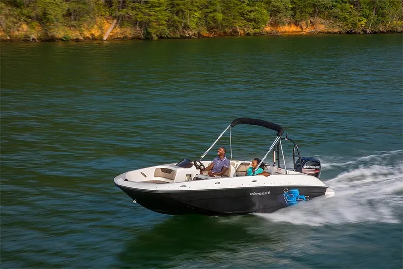 Slide: The Image of 2023 Bayliner Element E18 boat cruising on a lake with two passengers. - 25