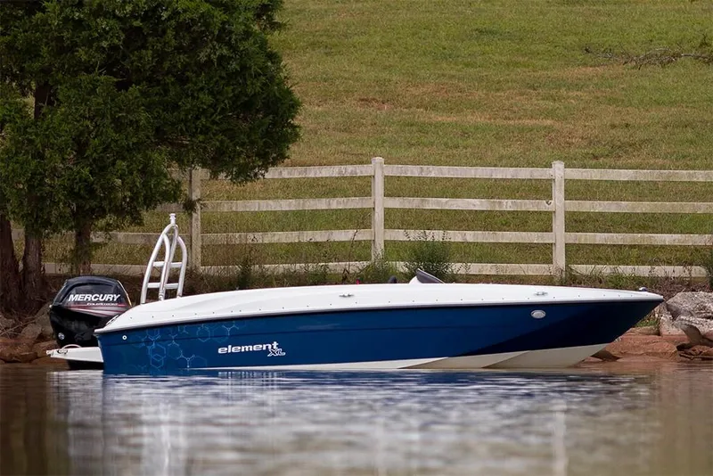 Slide: The Image of 2023 Bayliner Element E18 boat on a calm lake near a wooden fence. - 28