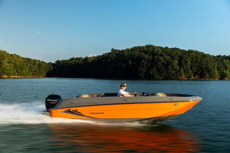 Slide: The Image of 2023 Bayliner Element E21 boat cruising on a lake with forested shoreline. - 13