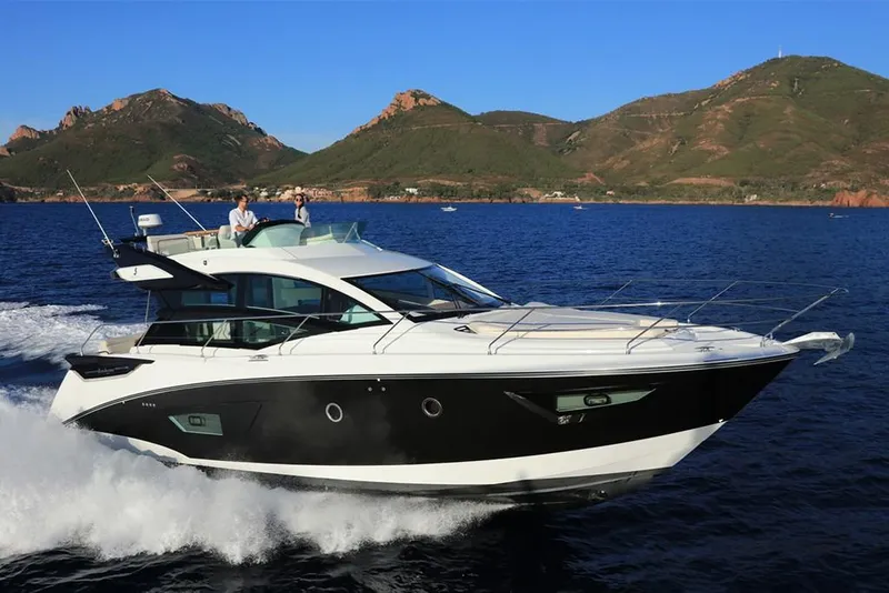 Slide: The Image of 2021 Beneteau Gran Turismo 50 Sportfly cruising on open water with scenic mountain backdrop. - 3