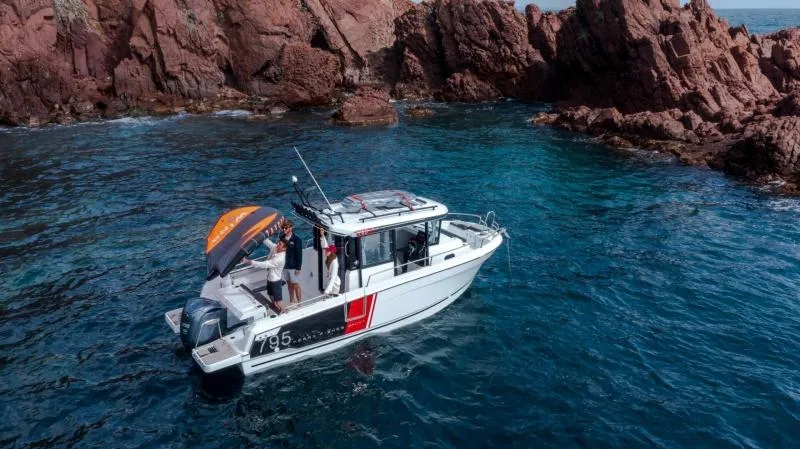 Slide: The Image of 2023 Jeanneau NC795 Sport Series 2 boat cruising on blue water near rocky coastline. - 16