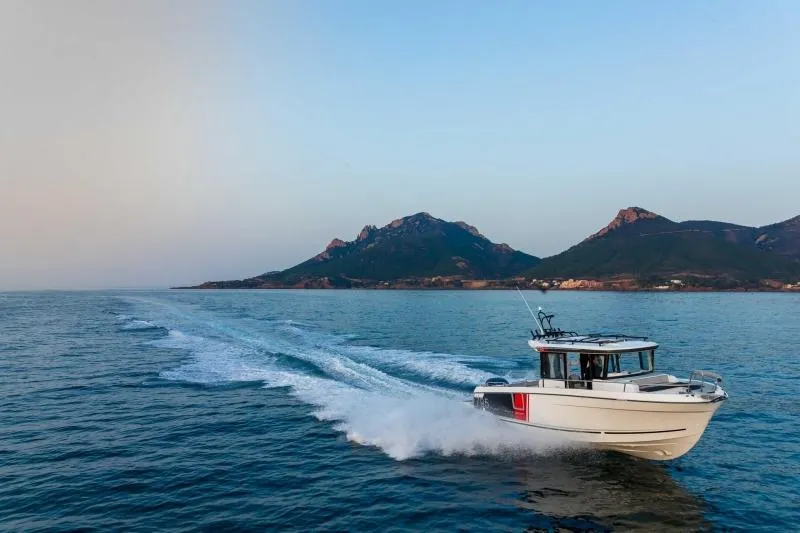 Slide: The Image of 2023 Jeanneau NC795 Sport Series 2 boat cruising on open water near a coastal town. - 32