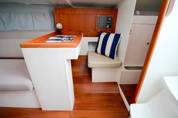 Slide: The Image of 2024 J Boats J/99 interior with wooden flooring, navigation station, and striped cushion. - 17