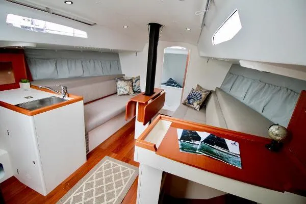 Slide: The Image of 2024 J Boats J/99 interior with modern design, featuring seating, kitchenette, and navigation table. - 23