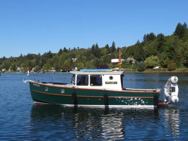 The Image of Devlin Surf Scoter 2000 boat on a calm lake with forested shoreline. - 0