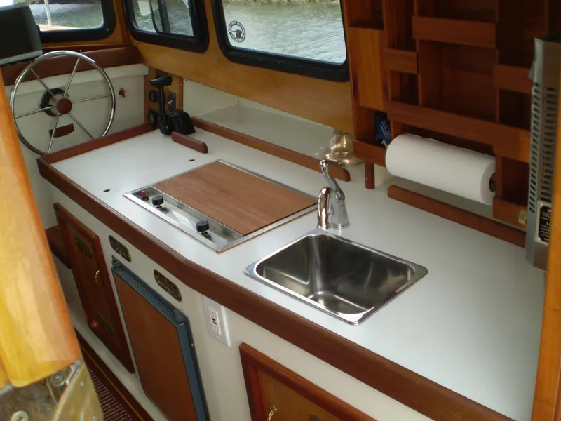 Slide: The Image of Compact kitchen area in a 2000 Devlin Surf Scoter boat, featuring a sink and stove. - 13