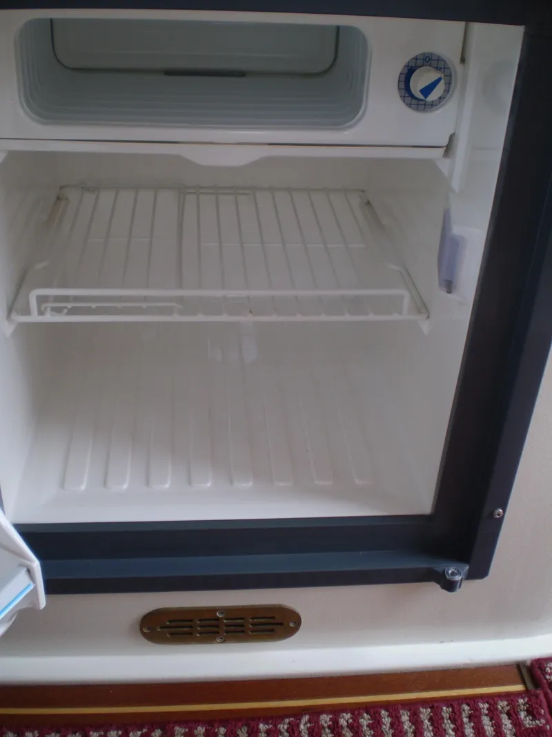 Slide: The Image of Open refrigerator inside a 2000 Devlin Surf Scoter boat, showing empty shelves. - 22