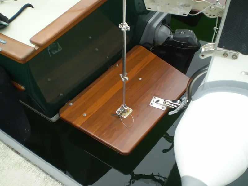 Slide: The Image of Devlin Surf Scoter 2000 boat with wooden swim platform and motor, docked on calm water. - 6