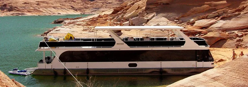 Slide: The Image of 2013 Bravada Tranquility Trip 17 houseboat docked by rocky shoreline. - 0