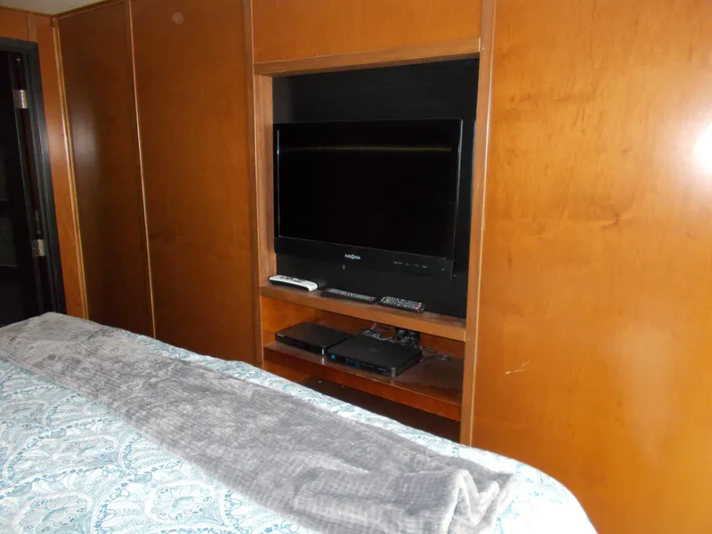 Slide: The Image of Built-in TV in Bravada Tranquility Trip 17, 2013 model, with wooden cabinetry and cozy bedding. - 10
